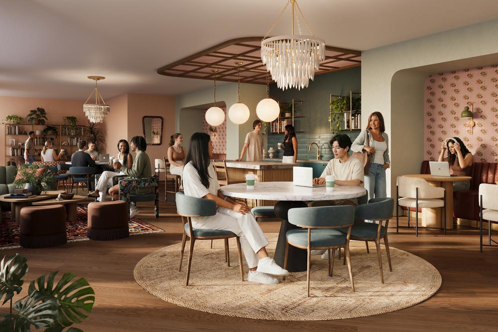 A modern, stylish café in Rambler Ann Arbor with people socializing, working on laptops, and chatting. The space features round tables, velvet chairs, warm lighting, plants, and decorative wallpaper for a cozy atmosphere.